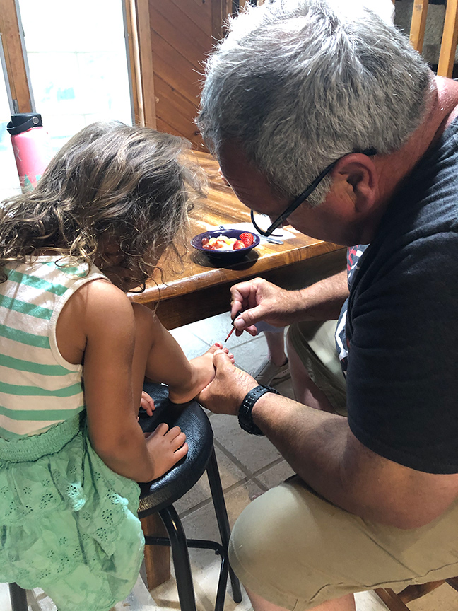 Grandpa Painting little girl's toes